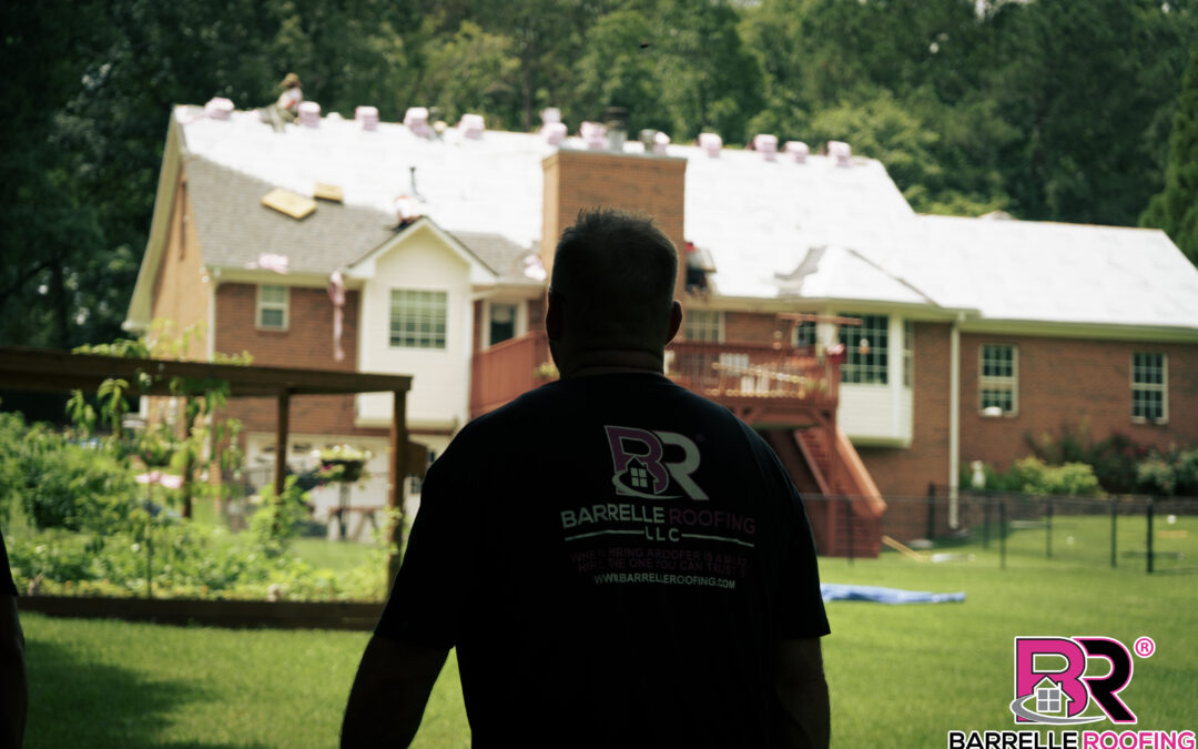 A man walks a yard as a new roof is being installed in the background