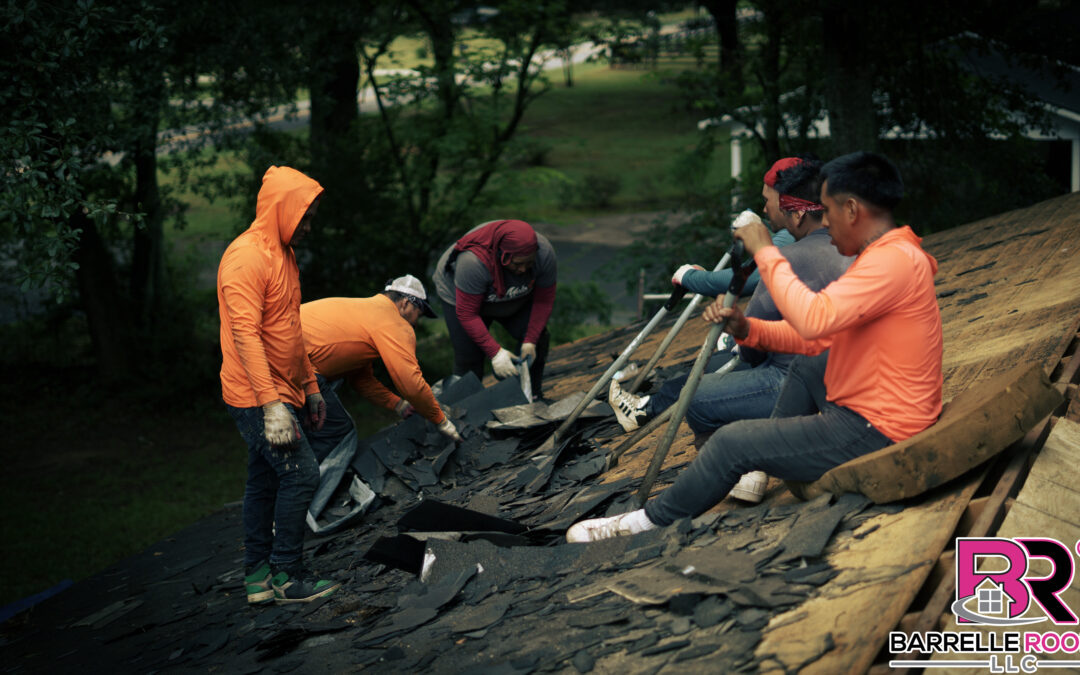 A group of roofers work together to remove old shingles from a roof